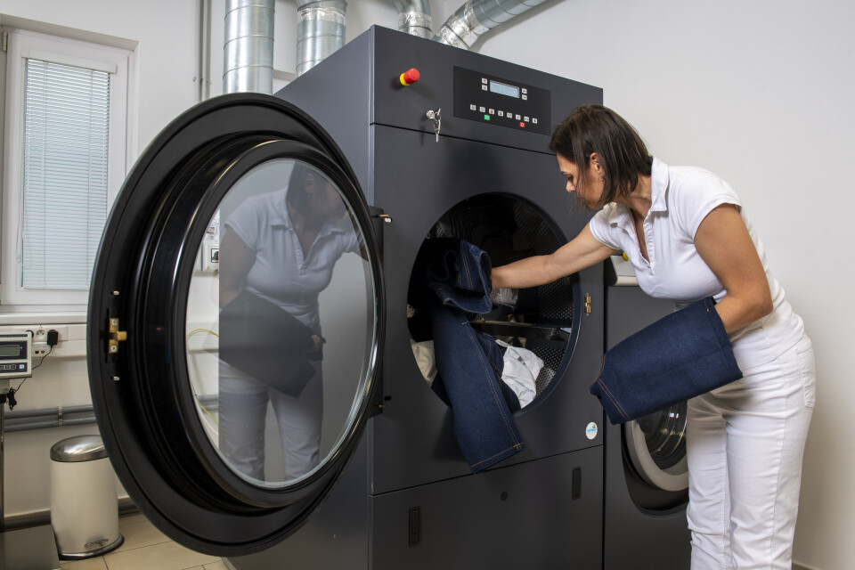 Fit and Proof Woman putting jeans in black washing machine 300